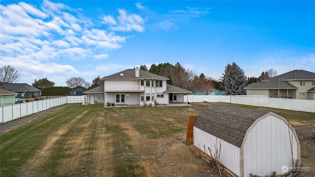 back of property with a storage unit, a yard, and a patio