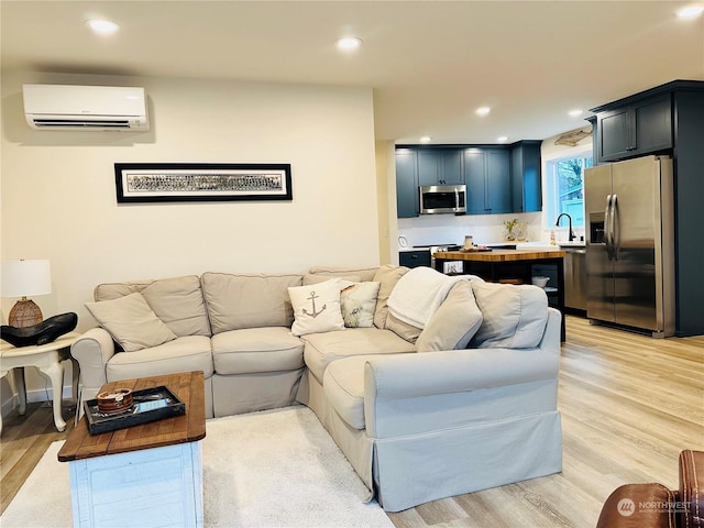 living room featuring sink, a wall mounted AC, and light wood-type flooring