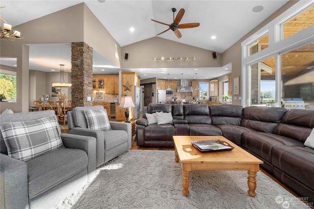 living room featuring ornate columns, ceiling fan with notable chandelier, and high vaulted ceiling