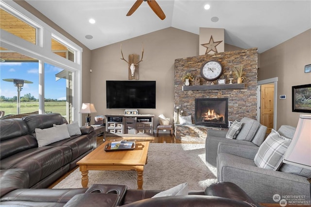 living room featuring ceiling fan, wood-type flooring, a stone fireplace, and high vaulted ceiling