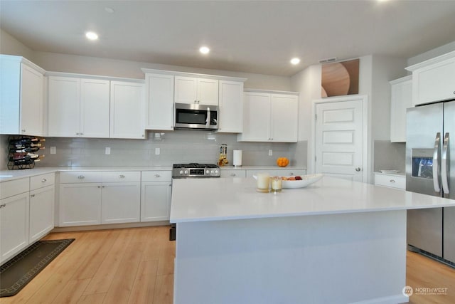 kitchen featuring backsplash, a kitchen island, white cabinets, and appliances with stainless steel finishes