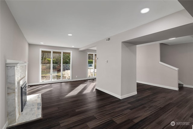 unfurnished living room featuring dark wood-type flooring and a high end fireplace