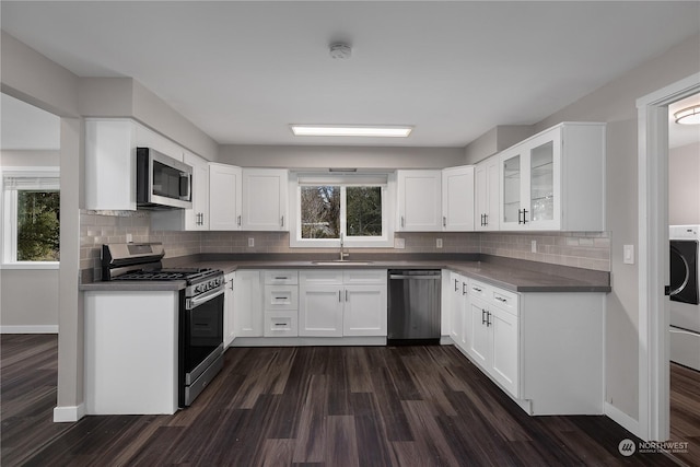 kitchen with sink, appliances with stainless steel finishes, white cabinetry, backsplash, and dark hardwood / wood-style flooring