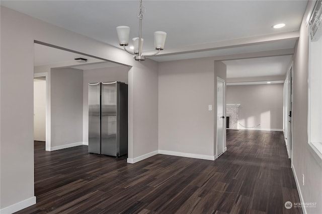 unfurnished room with an inviting chandelier and dark wood-type flooring