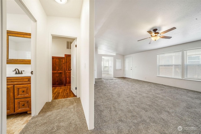 hall with light colored carpet, sink, and a textured ceiling