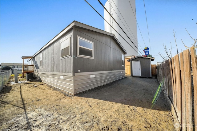 view of side of home featuring central AC and a shed