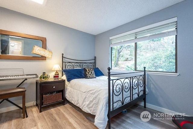 bedroom featuring a textured ceiling, baseboards, and wood finished floors