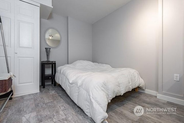 bedroom featuring lofted ceiling, baseboards, and wood finished floors