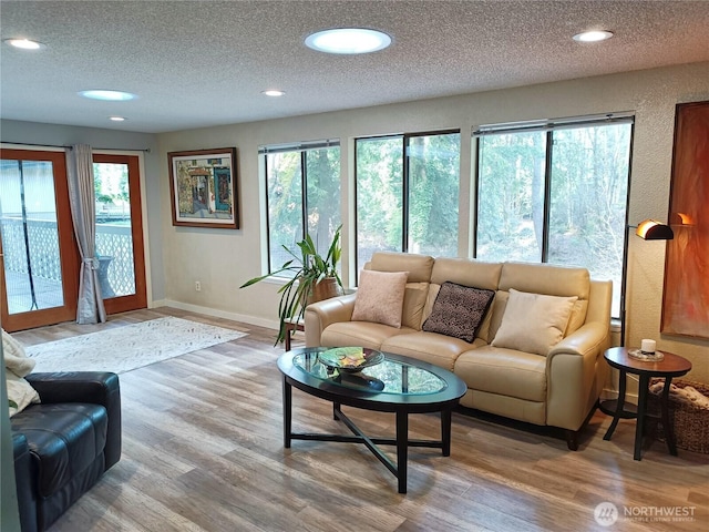 living room featuring recessed lighting, a healthy amount of sunlight, a textured ceiling, and wood finished floors