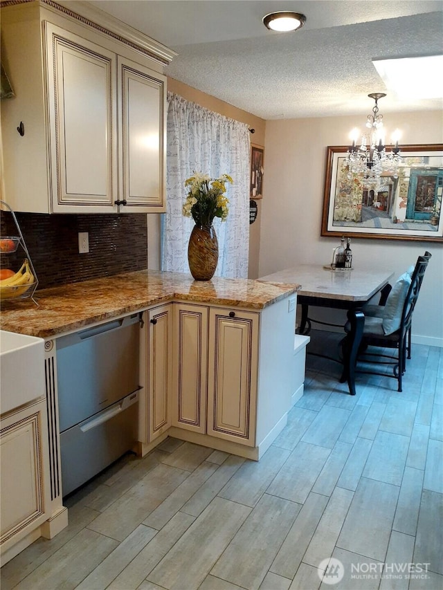 kitchen with wood finish floors, cream cabinetry, a peninsula, and an inviting chandelier