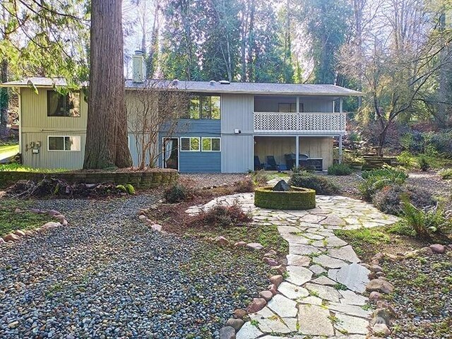 back of property with a sunroom, a chimney, a fire pit, and a patio