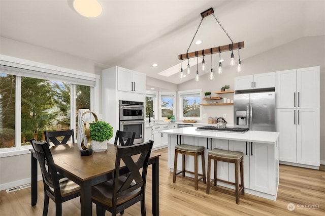 dining area featuring lofted ceiling, sink, and light hardwood / wood-style floors