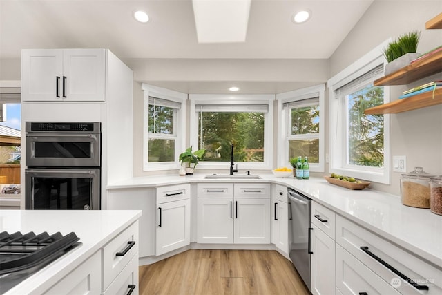 kitchen featuring stainless steel appliances, sink, white cabinets, and light wood-type flooring