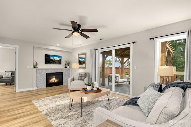 living room featuring ceiling fan, wood-type flooring, and a tile fireplace