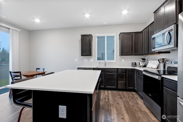 kitchen featuring sink, light wood-type flooring, stainless steel appliances, and a kitchen island