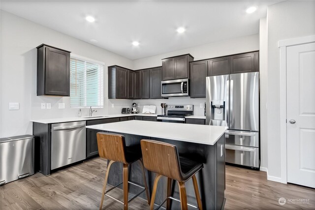 kitchen featuring sink, a breakfast bar area, a center island, dark brown cabinets, and stainless steel appliances