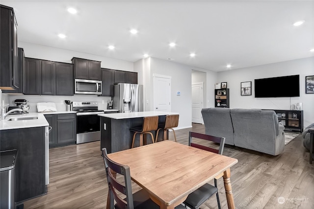 kitchen featuring stainless steel appliances, sink, a kitchen island, and light wood-type flooring