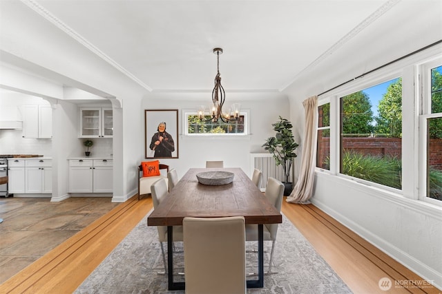 dining area with an inviting chandelier, light hardwood / wood-style flooring, and ornamental molding