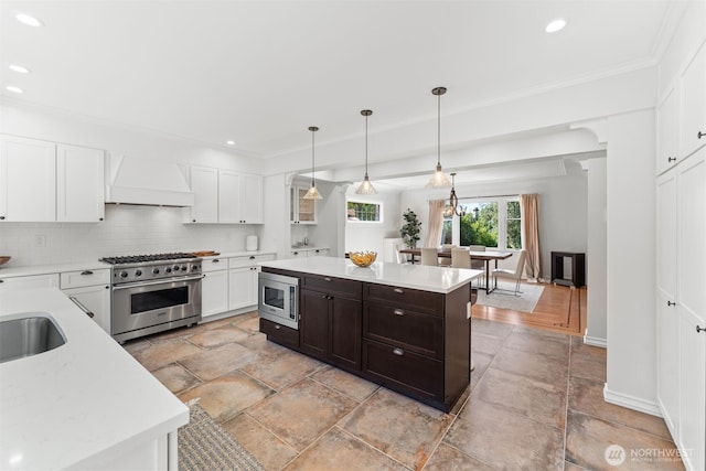 kitchen with premium range hood, appliances with stainless steel finishes, tasteful backsplash, white cabinetry, and a center island