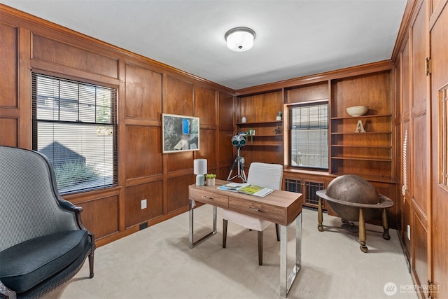 office area with light colored carpet and wooden walls