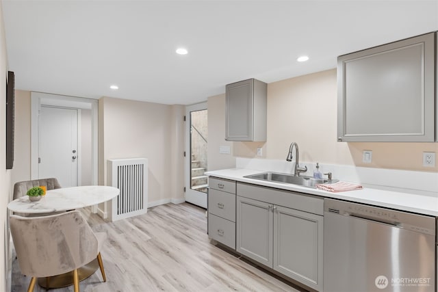 kitchen with sink, radiator, light hardwood / wood-style flooring, dishwasher, and gray cabinetry