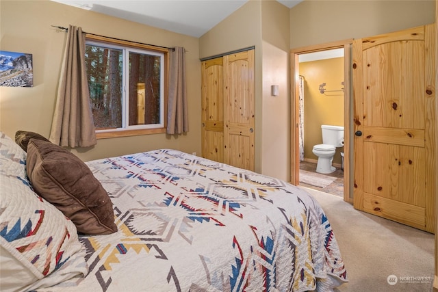 carpeted bedroom featuring lofted ceiling, a closet, and ensuite bathroom