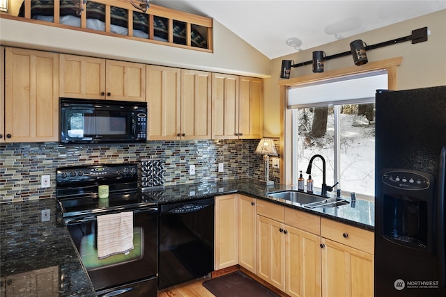 kitchen featuring vaulted ceiling, dark stone countertops, sink, and black appliances