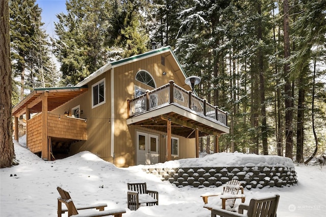 snow covered rear of property with a deck