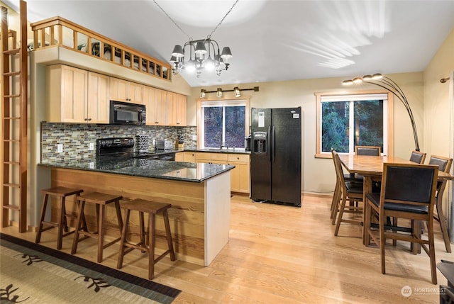 kitchen with sink, an inviting chandelier, dark stone countertops, kitchen peninsula, and black appliances