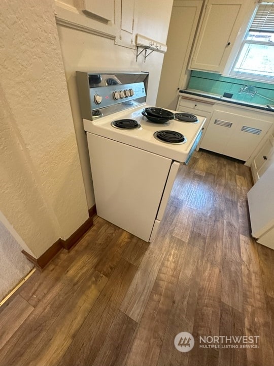 kitchen with white range with electric cooktop, dark hardwood / wood-style floors, and white cabinets