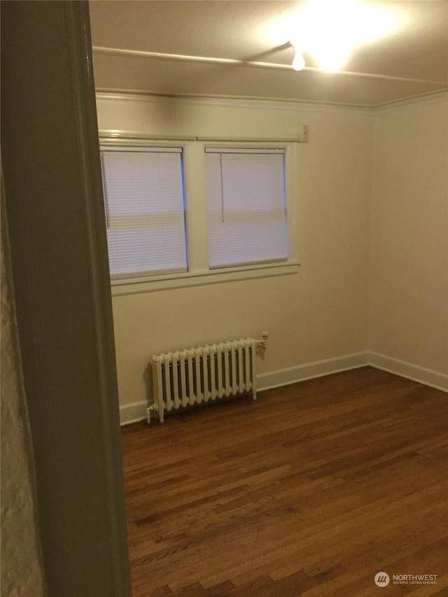 unfurnished room featuring radiator heating unit and dark hardwood / wood-style flooring