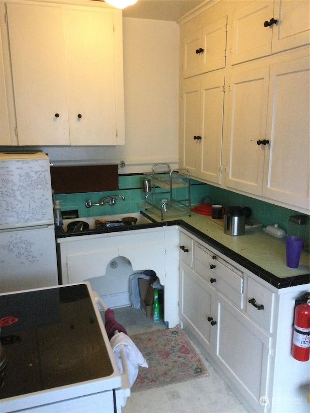 kitchen with white cabinetry, sink, and white fridge