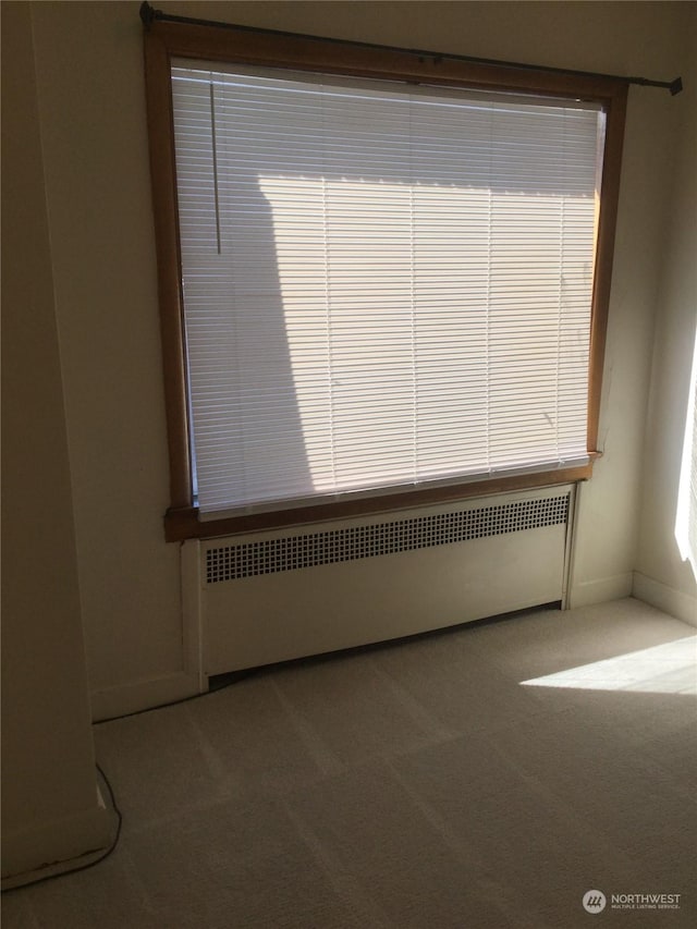 unfurnished room featuring carpet floors and radiator