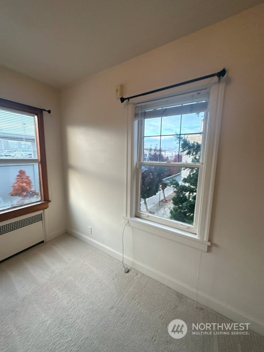 carpeted empty room featuring a healthy amount of sunlight and radiator