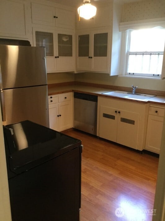 256 Burwell St, Bremerton, WA 98337 - kitchen with stainless steel appliances, light wood-style floors, white cabinetry, and glass insert cabinets