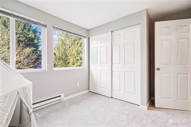 unfurnished bedroom featuring a baseboard radiator, light colored carpet, and a closet