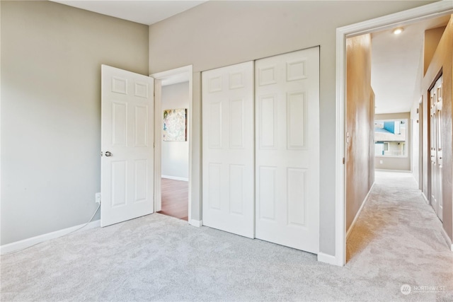 unfurnished bedroom featuring light carpet and a closet