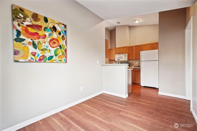 kitchen featuring high vaulted ceiling, white appliances, and light hardwood / wood-style floors