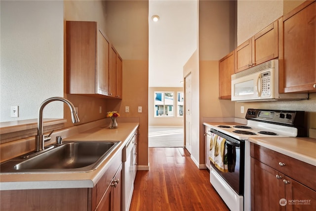 kitchen featuring white appliances, dark hardwood / wood-style flooring, and sink