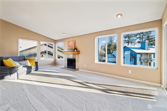 carpeted living room with vaulted ceiling and a tile fireplace