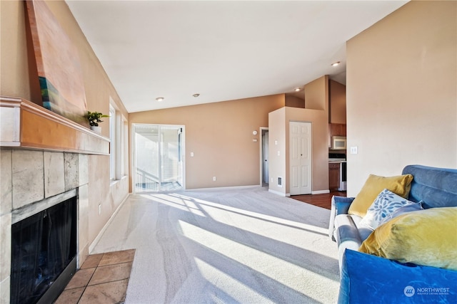 carpeted living room featuring a tile fireplace and vaulted ceiling