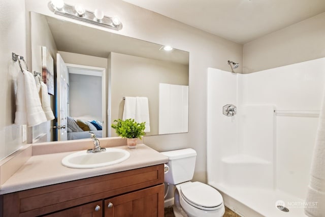 bathroom with walk in shower, vanity, and toilet