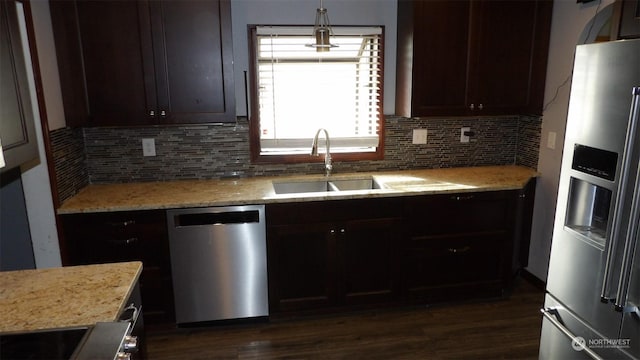 kitchen with pendant lighting, appliances with stainless steel finishes, light stone countertops, and sink