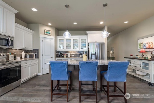 kitchen featuring hanging light fixtures, appliances with stainless steel finishes, and white cabinets