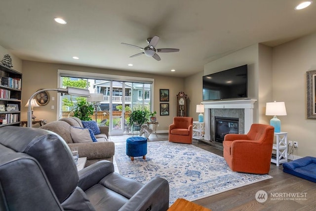 living room featuring hardwood / wood-style flooring, a tile fireplace, and ceiling fan