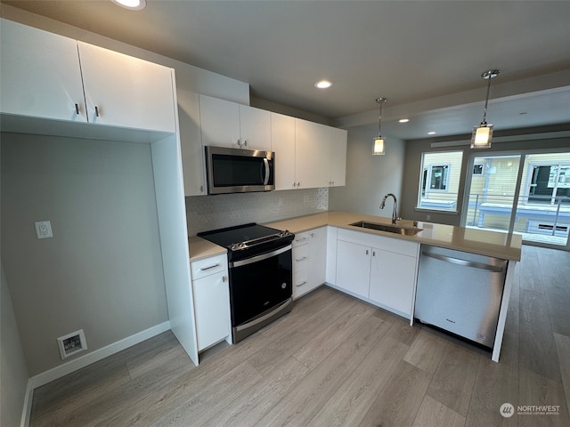 kitchen featuring sink, hanging light fixtures, stainless steel appliances, white cabinets, and kitchen peninsula