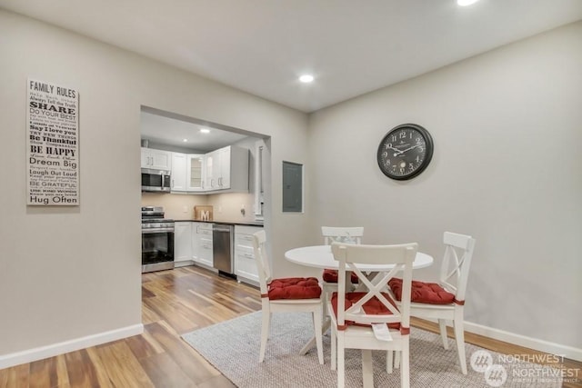 dining area with electric panel and light wood-type flooring