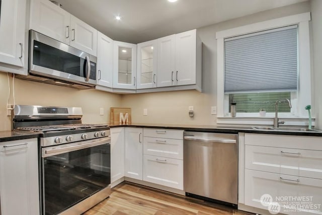 kitchen featuring white cabinetry, appliances with stainless steel finishes, light hardwood / wood-style floors, and sink