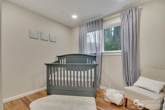 bedroom featuring hardwood / wood-style floors and a crib