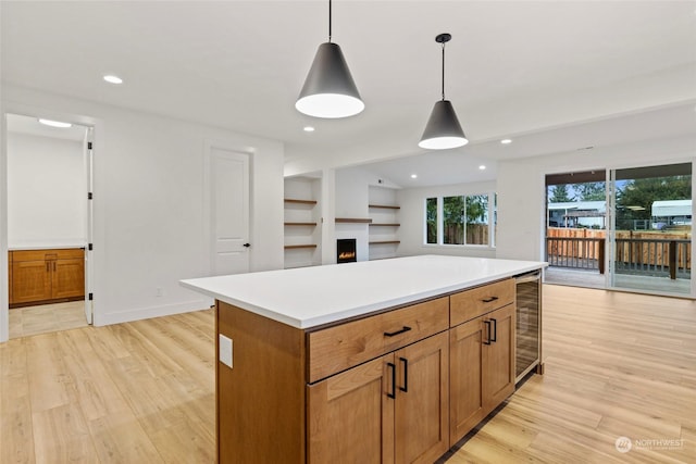 kitchen featuring a center island, pendant lighting, brown cabinets, light countertops, and open floor plan